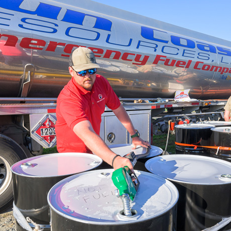 Volunteer filling up a barrel with fuel